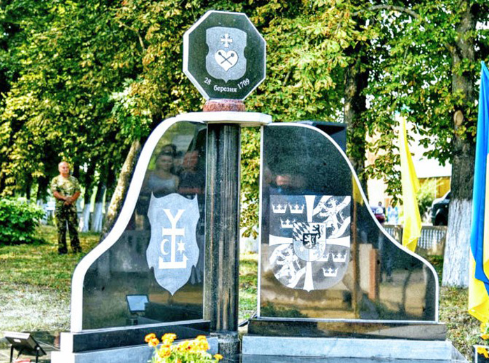На пам’ятному знакові зобразили герби учасників тих історичних подій, а увічнює пам’ятник герб сотенного козацького містечка Великі Будища 1709 року. Фото з сайту «Полтавщина»
